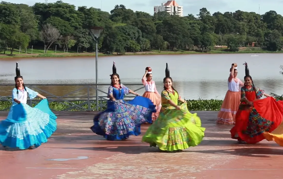 Vrouwen in klederdracht dansen de Paraguayaanse flessendans aan het Lago de la República in Ciudad del Este