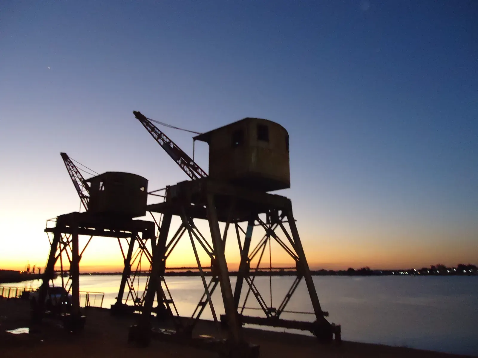 Silhouetten van oude havenkranen in de haven van Asunción aan de Río Paraguay bij zonsondergang, de rivier die voor de export van Paraguay onmisbaar is