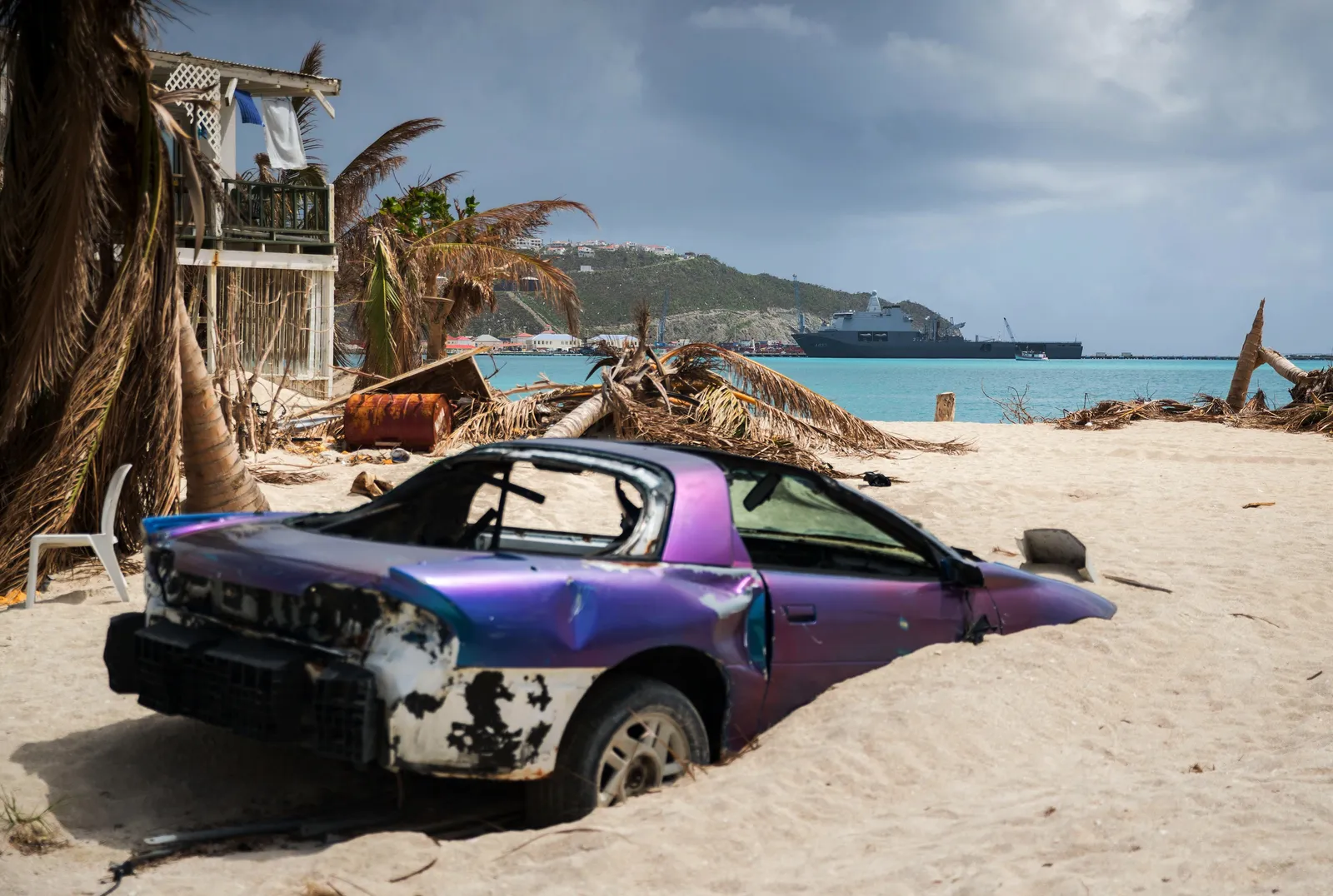Strand van Philipsburg op Sint Maarten na orkaan Irma in 2017, met een autowrak en geknakte palmen