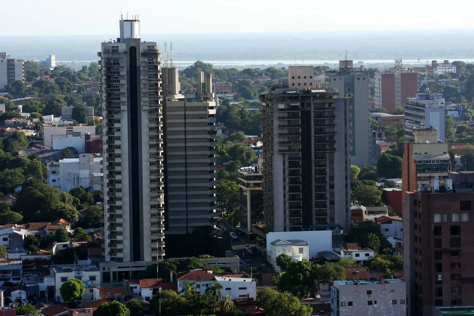 Appartementstorens tussen het groen van Asunción met de rivier de Paraguay op de achtergrond, typisch vastgoed voor een belegging met huurrendement