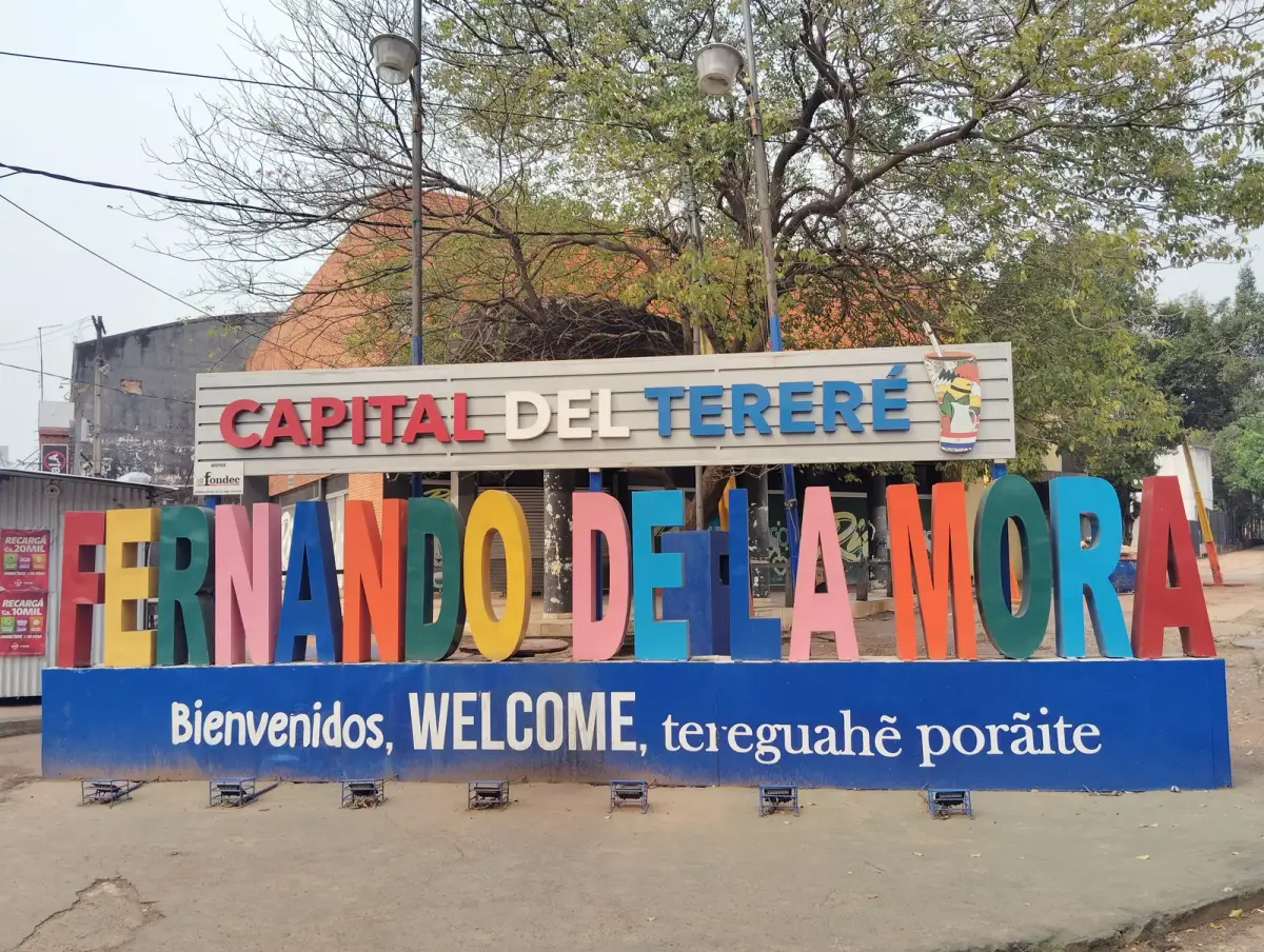 Kleurrijk welkomstbord Capital del Tereré in Fernando de la Mora bij Asunción met de tekst in Spaans, Engels en Guaraní, de talen waarmee u bij zaken doen in Paraguay te maken krijgt